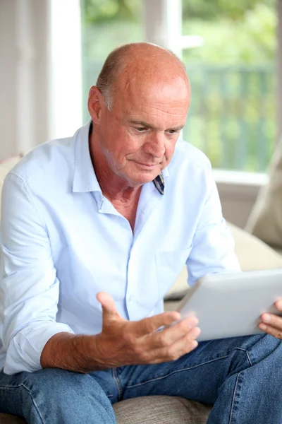 Uomo anziano che utilizza tablet elettronico a casa — Foto Stock