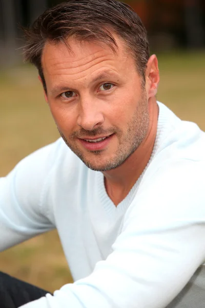 Portrait of handsome man sitting in park — Stock Photo, Image