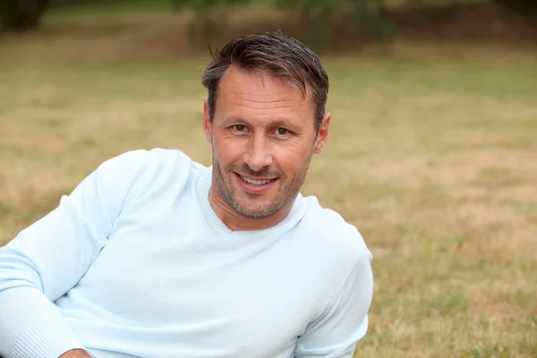 Portrait of handsome man sitting in park — Stock Photo, Image