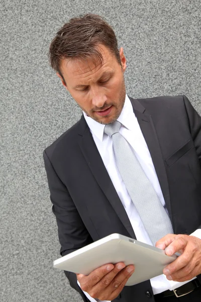 Zakenman met behulp van elektronische tablet leunde tegen muur — Stockfoto