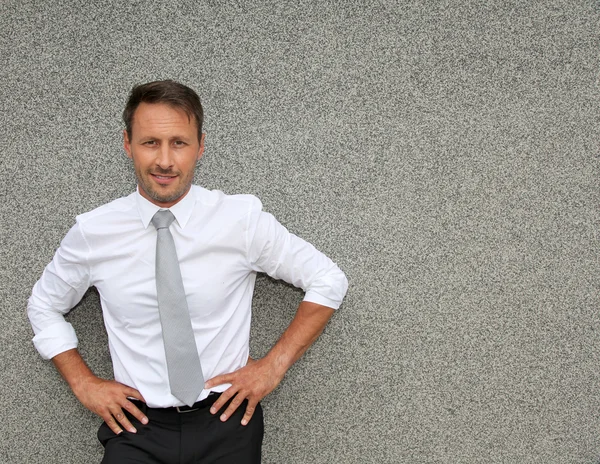 Businessman standing against concrete wall — Stock Photo, Image