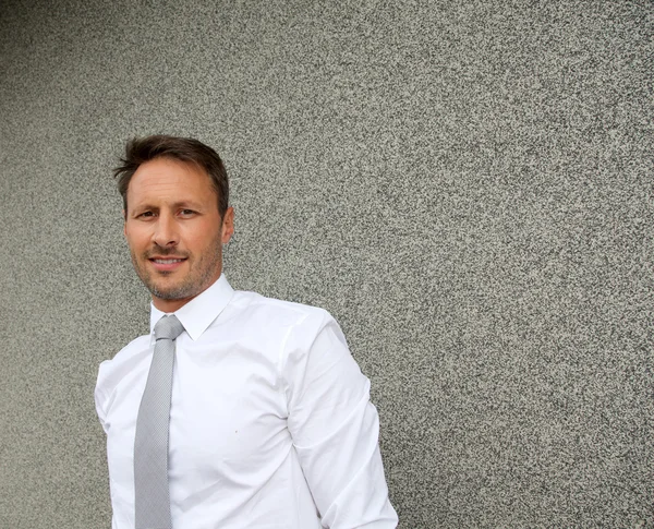 Businessman standing against concrete wall — Stock Photo, Image