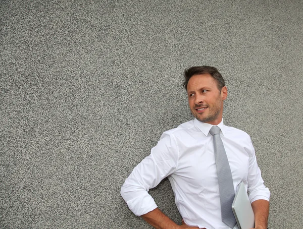 Businessman standing against concrete wall — Stock Photo, Image