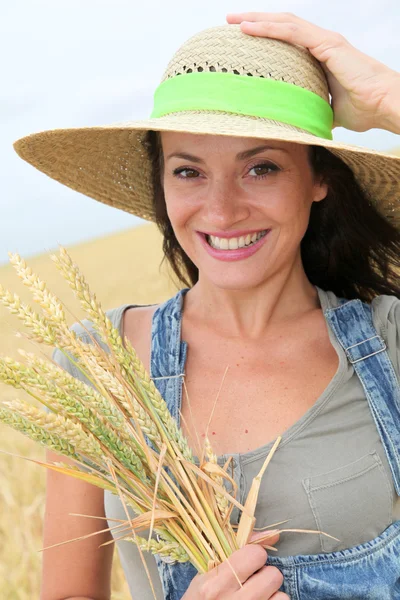 Όμορφη γυναίκα με ψάθινο καπέλο στέκεται στο χωράφι με το σιτάρι — Φωτογραφία Αρχείου