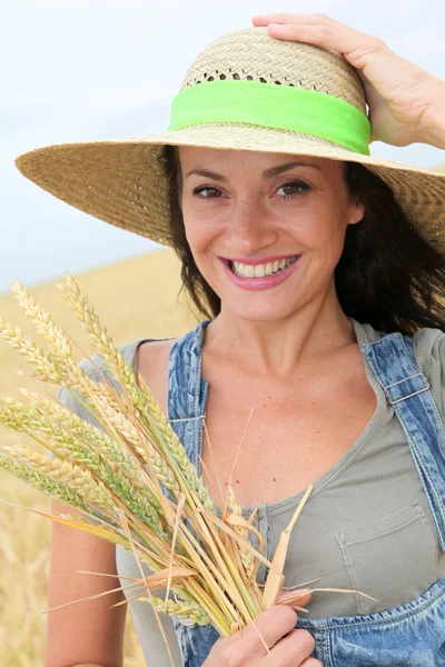 Hermosa mujer con sombrero de paja de pie en el campo de trigo —  Fotos de Stock