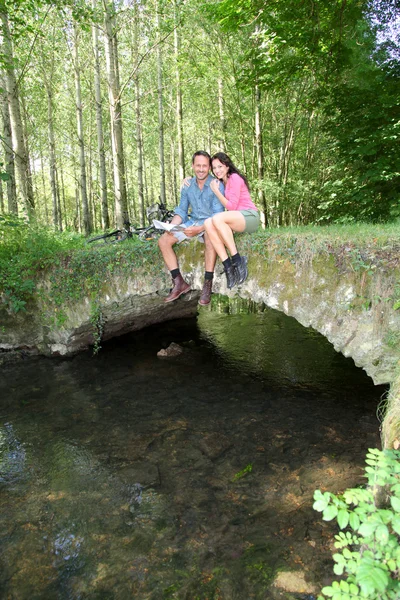 Paar zittend op een brug in bos — Stockfoto