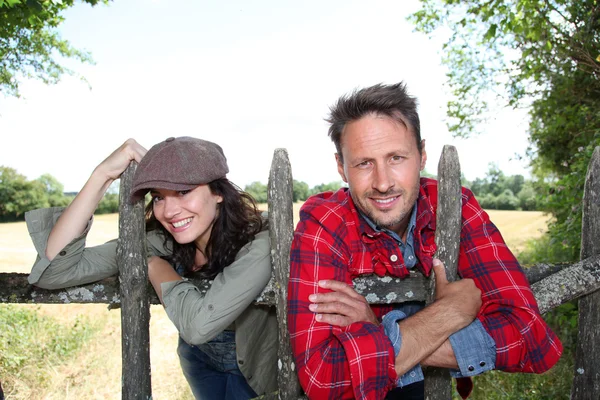 Couple leaning on fence in country field — Stock Photo, Image