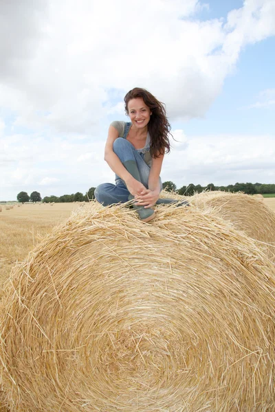 Frau hat Spaß auf Heuballen zu sitzen — Stockfoto