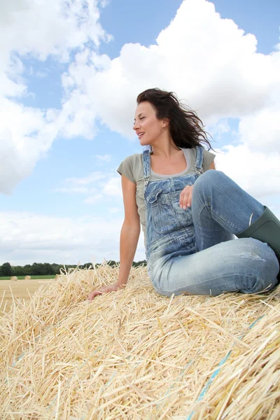 Žena bavit sedět na balíku sena — Stock fotografie