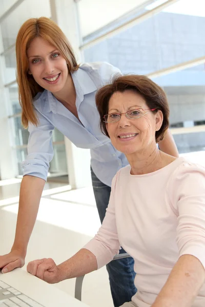Senior woman with trainer in front of computer — Stock Photo, Image