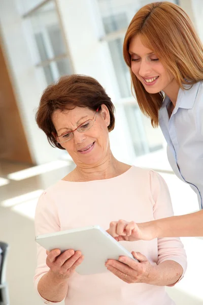 Femme âgée apprenant à utiliser une tablette électronique — Photo