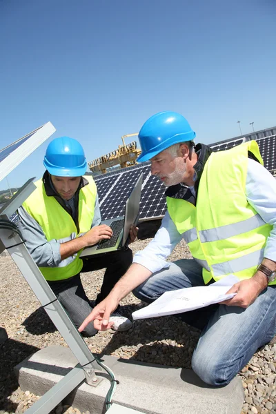 Ingenieros revisando paneles solares funcionando — Foto de Stock