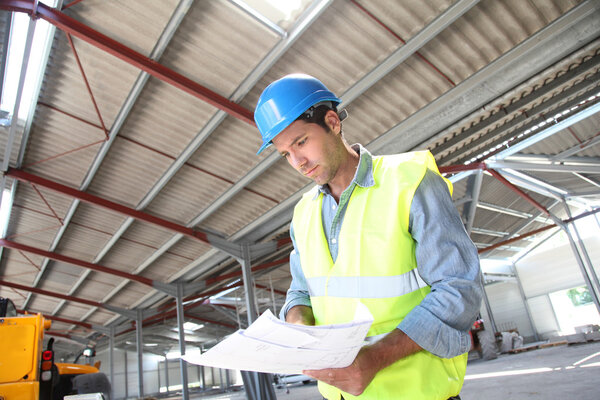 Engineer checking plan in building under construction