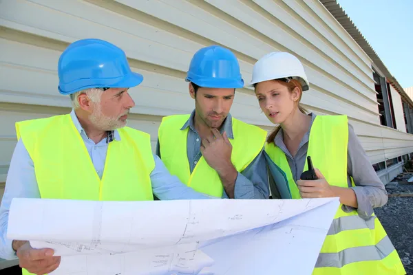 Workteam checking plan on construction site — Stock Photo, Image