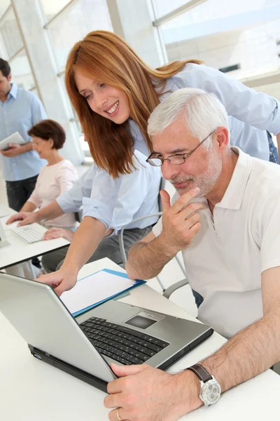 Senior man with trainer in front of laptop computer — Stock Photo, Image