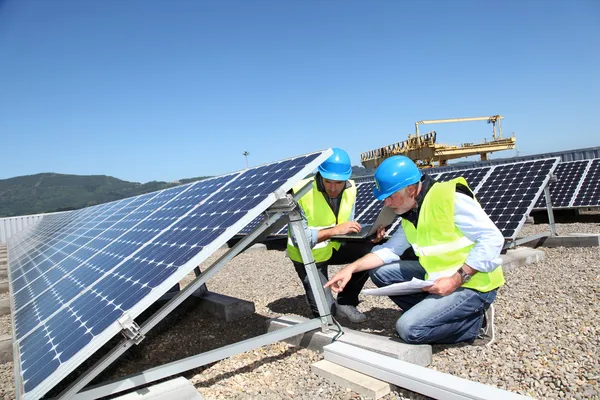 Engenheiros verificando painéis solares em execução — Fotografia de Stock