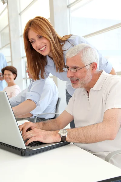 Senior man with trainer in front of laptop computer Stock Image