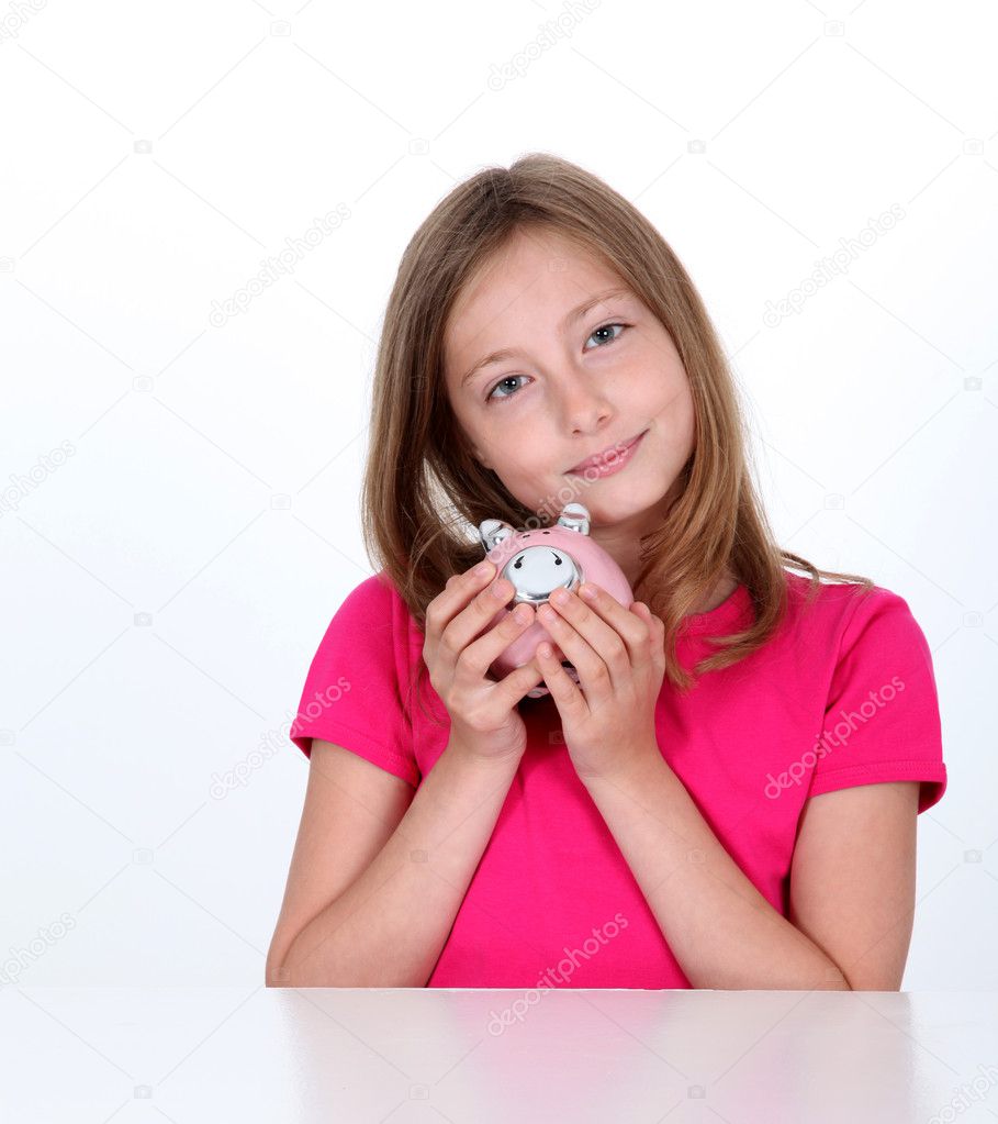 Smiling young girl holding piggy bank