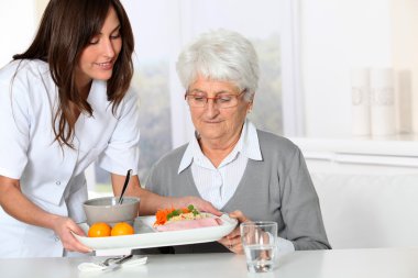 yemek tepsisi Huzurevi yaşlı kadına getiren güzel hemşire