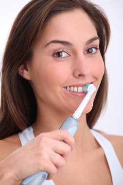 Closeup of beautiful woman brushing her teeth clipart