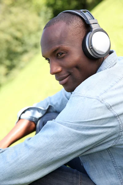 Man relaxing in garden with headphones on — Stock Photo, Image