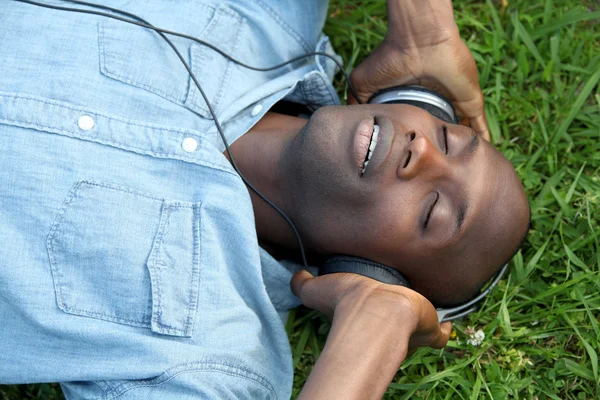 Man laying down in garden with headphones on — Stock Photo, Image