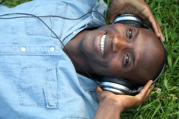 Mann legt sich mit Kopfhörer in Garten — Stockfoto