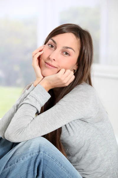 Sorridente giovane donna a casa seduta sul divano — Foto Stock