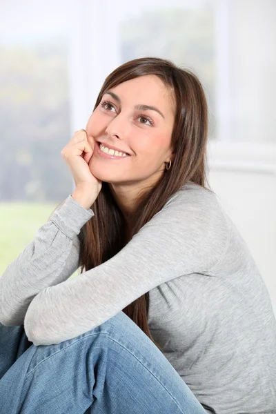 Sorridente giovane donna a casa seduta sul divano — Foto Stock