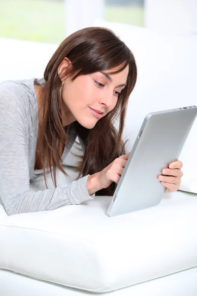 Mujer joven sentada en sofá con almohadilla electrónica — Foto de Stock