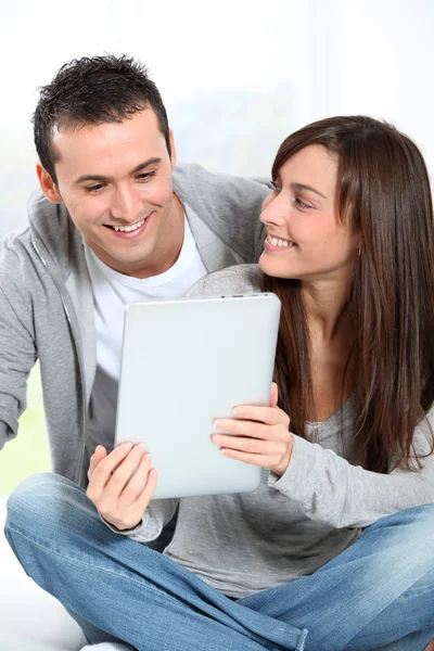 Junges Paar sitzt auf Sofa mit elektronischem Pad — Stockfoto