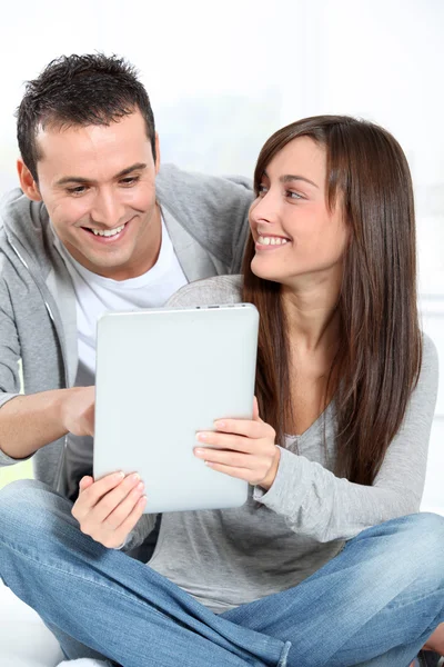 Young couple sitting on sofa with electronic pad — Stock Photo, Image