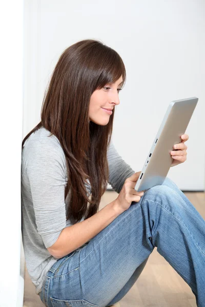 Elektronik pad ile katta oturan genç kadın — Stok fotoğraf