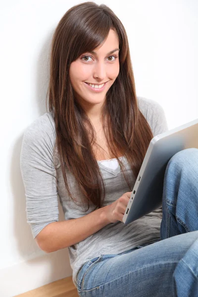 Mujer joven sentada en el suelo con almohadilla electrónica —  Fotos de Stock