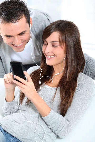 Jong koppel luisteren naar muziek met mobiele telefoon — Stockfoto