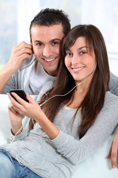 Jovem casal ouvindo música com telefone celular — Fotografia de Stock