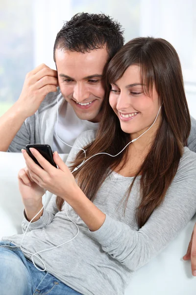 Молодая пара слушает музыку с мобильного телефона — стоковое фото
