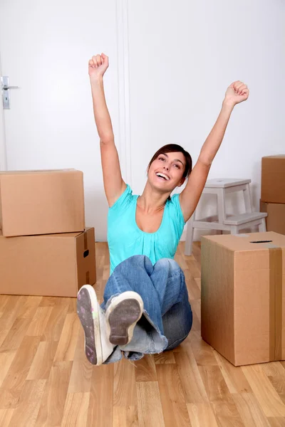 Bella giovane donna seduta accanto a scatole in nuova casa — Foto Stock