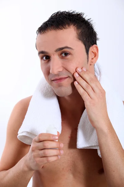 Крупный план молодого человека с увлажняющим кремом на лице — стоковое фото
