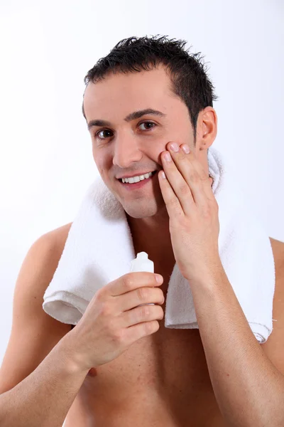 Primer plano del joven poniendo crema hidratante en su cara — Foto de Stock