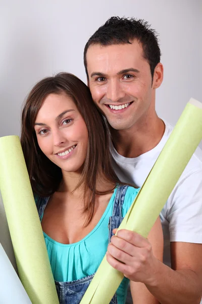 Fechar-se de jovem casal segurando rolos de papel de parede — Fotografia de Stock