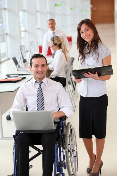 Empresário em cadeira de rodas com assistente no escritório — Fotografia de Stock