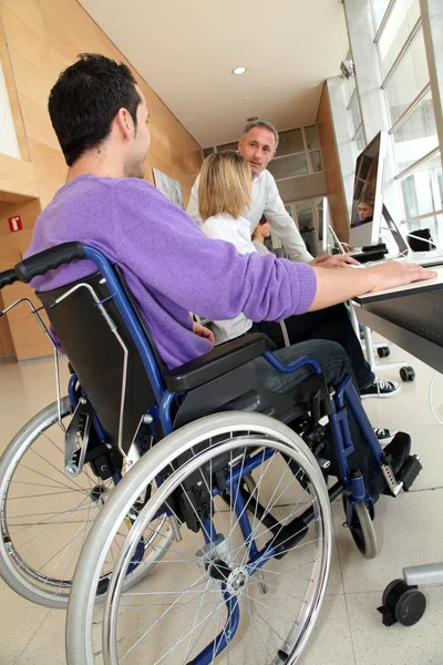 Человек в инвалидной коляске работает в офисе — стоковое фото