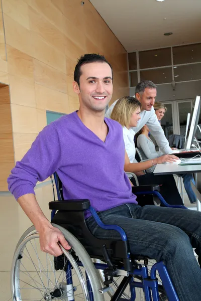Человек в инвалидной коляске работает в офисе — стоковое фото