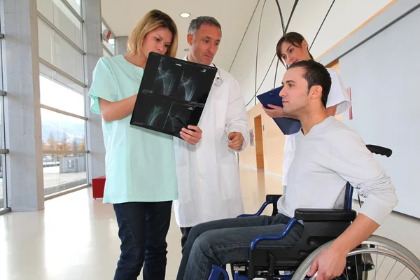 Медицинская команда с инвалидом смотрит на рентген — стоковое фото
