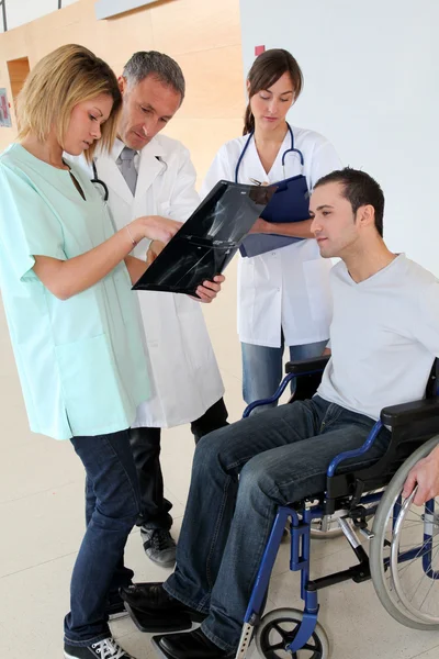 Медицинская команда с инвалидом смотрит на рентген — стоковое фото
