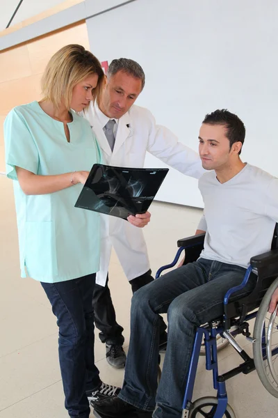 Medical team with handicapped person looking at X-ray — Stock Photo, Image