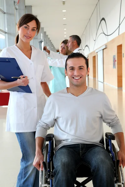 Hermosa enfermera de pie por el hombre en silla de ruedas — Foto de Stock