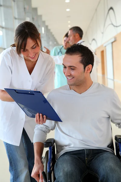 Красивая медсестра, стоящая рядом с человеком в инвалидном кресле — стоковое фото