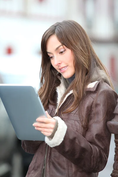 Mujer joven usando almohadilla electrónica en la ciudad — Foto de Stock